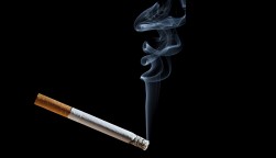 Cigarette with blue smoke on black background