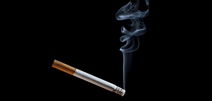 Cigarette with blue smoke on black background