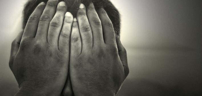 a black and white image of a man holding his hands over his face