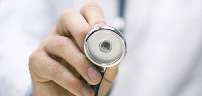 a doctors hand holding up a stethoscope