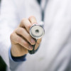 a doctors hand holding up a stethoscope