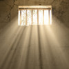 light shining through bars of prison window 