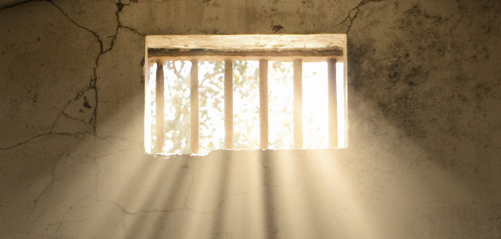 light shining through bars of prison window 
