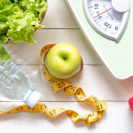 Green apple and Weight scale,measure tape with fresh vegetable, clean water and sport equipment for women diet slimming