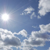 bright sun shining in blue sky with white clouds