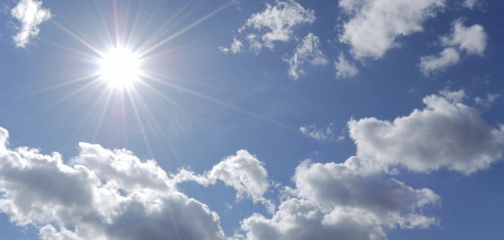 bright sun shining in blue sky with white clouds