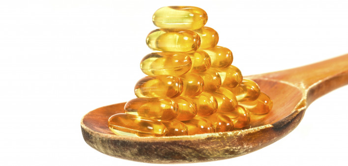 Vitamin D Capsules on wooden spoon