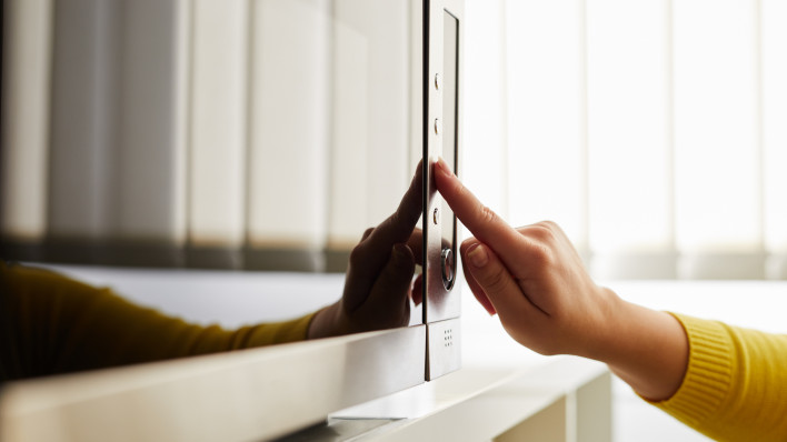 finger pushing button on microwave