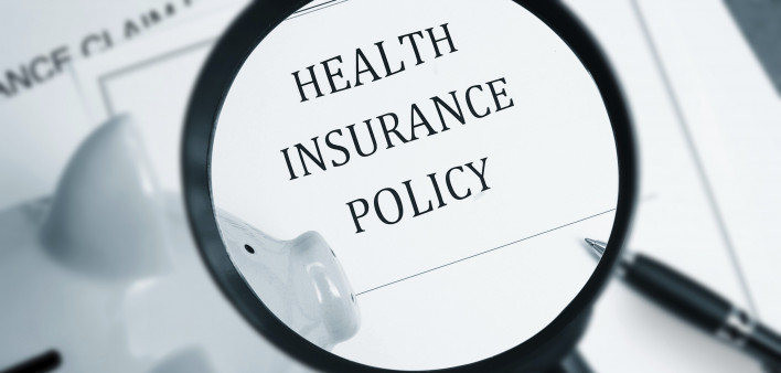 A maginfying glass looking at the words "Health Insurance Policy"