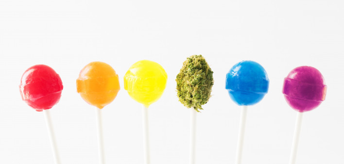 Lollipops in the colors of the rainbow, with a green marijuana bud on a lollipop stick in the middle.