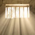 light shining through bars of prison window 