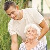 elderly woman having yoga lesson outside with insturctor