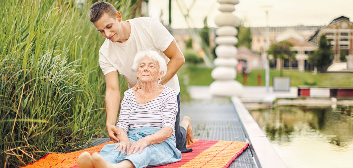 elderly woman having yoga lesson outside with insturctor