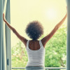 woman parting curtains of window in the morning