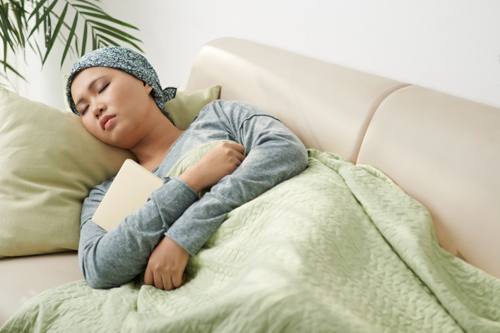 Asian woman with cancer sleeping on couch