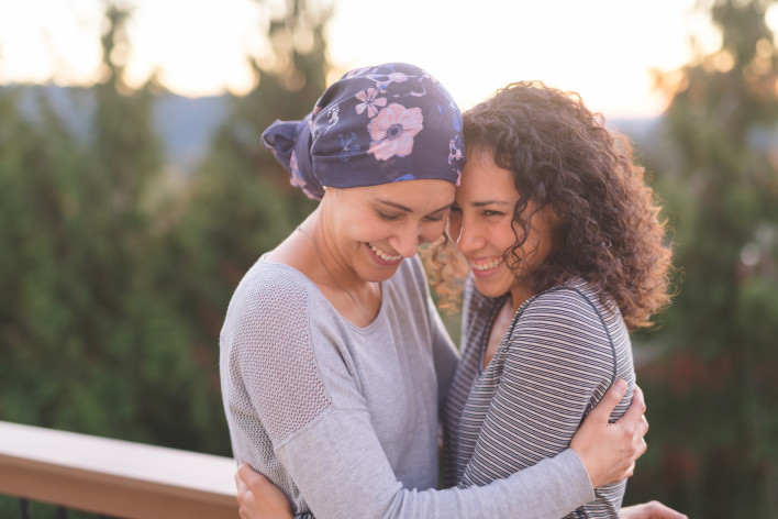 Beautiful ethnic woman battling cancer hugs her sister tightly