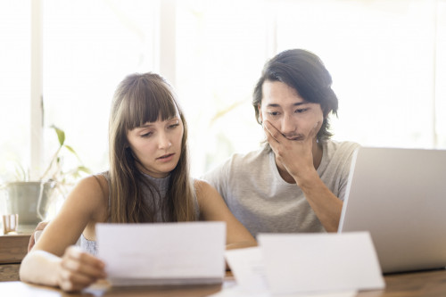 Tensed young couple reading document at home