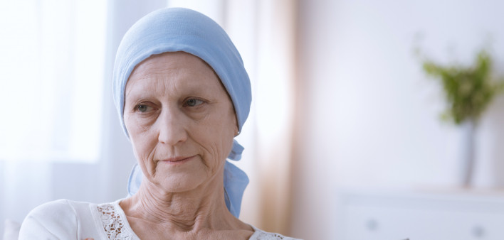 Sad depressed woman suffering from malignant breast cancer sitting alone