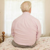 older man sitting on bed with back to camera