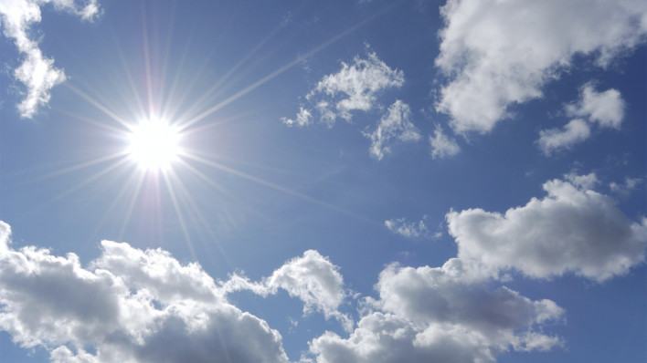 bright sun shining in blue sky with white clouds