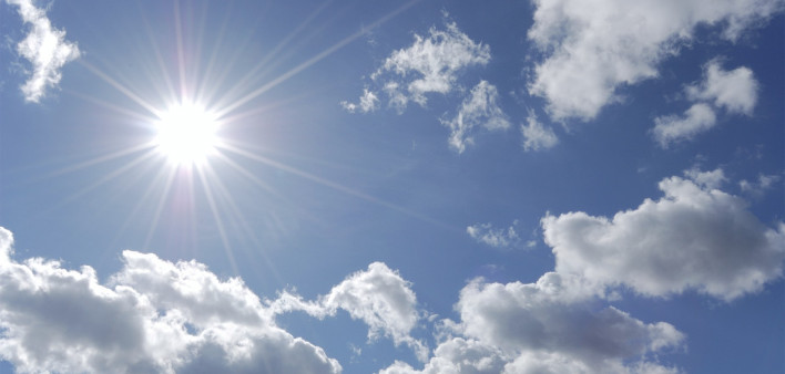 bright sun shining in blue sky with white clouds