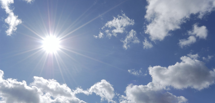 bright sun shining in blue sky with white clouds