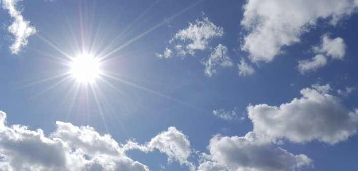 bright sun shining in blue sky with white clouds