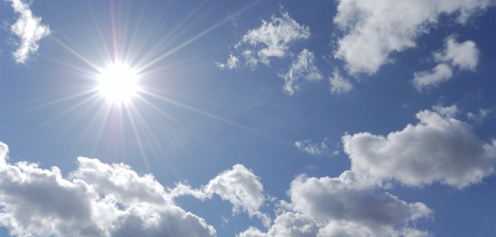bright sun shining in blue sky with white clouds