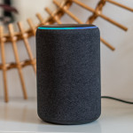Amazon Alexa Echo Plus on a white table with green plants in the background