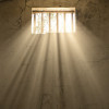 light shining through bars of prison window 