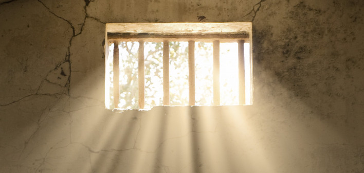 light shining through bars of prison window 