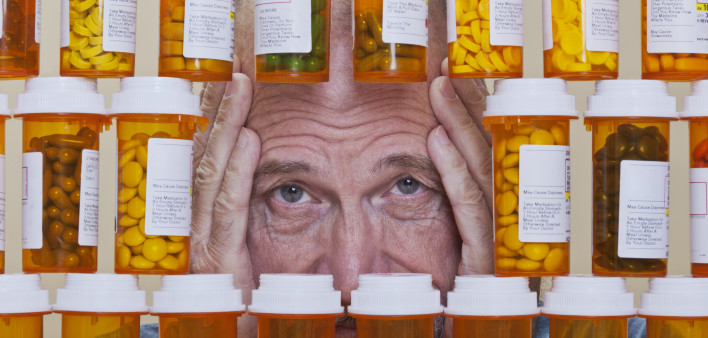 Depressed Senior Man Looking Through Rows of Prescription Medication