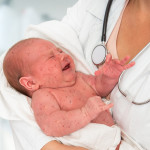 Doctor holding a newborn baby which is sick rubella or measles