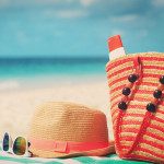 beach bag, sun glasses, sun hat on towel at beach ocean in the background