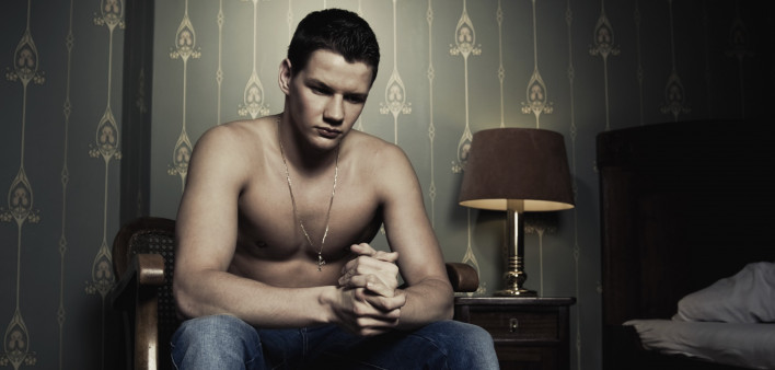 a shirtless man sitting in a bedroom at night