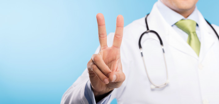 a doctor in white jacket making a peace sign with his fingers