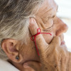 old woman with red string tied around index finger