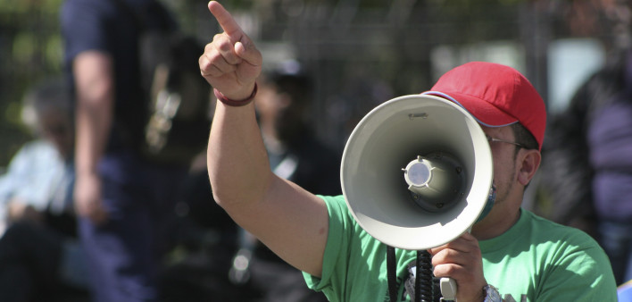 a protester speaking into a megaphone and pointing his finger