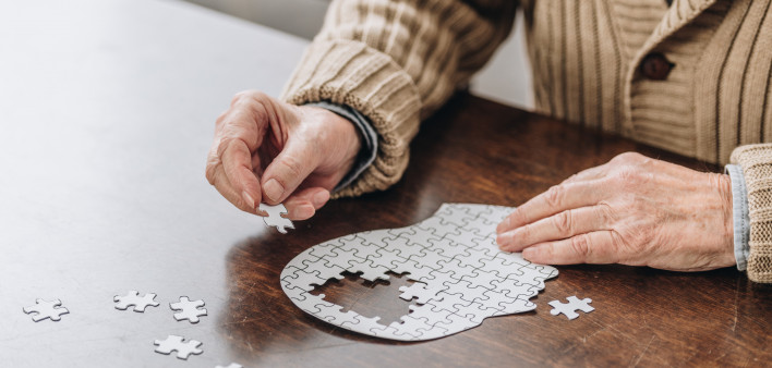 mans hands putting together puzzle pieces to make a head