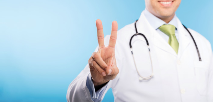 a doctor in white jacket making a peace sign with his fingers