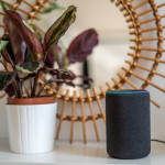 Amazon Alexa Echo Plus on a white table with green plants in the background
