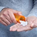 man taking pills pills in his hand