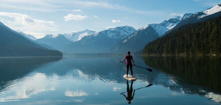 Woman stand up paddle boarding on a pristine mountain lake