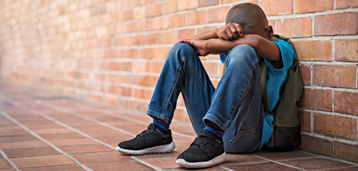 black boy sitting on floor hands in arms sad