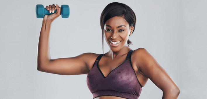 black woman in workout gear lifting a dumbell