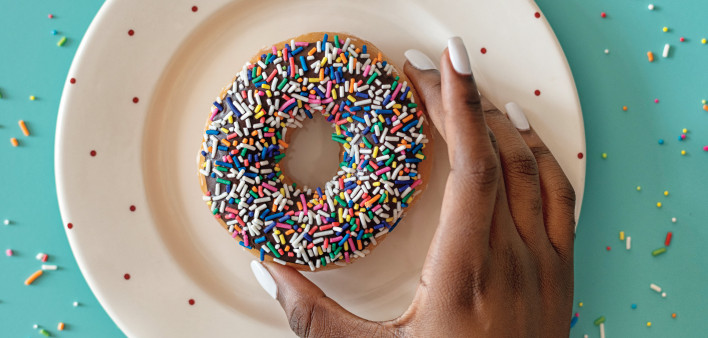 hand picking up donut with sprinkles
