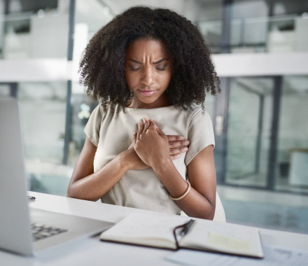 Cropped shot of an attractive young businesswoman holding her chest in pain while sitting in her office