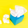 blue tissue box and white tissues on a yellow background