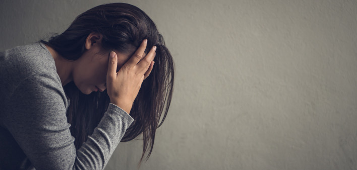 Depressed woman sitting on a chair in dark room at home. Lonely , sad