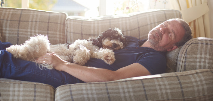 man sleeping on couch with his dog